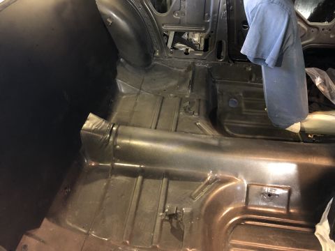 1968 Mercury Cougar - The bare metal floor pan of a vehicle is visible, showing structural details and preparation for further work.