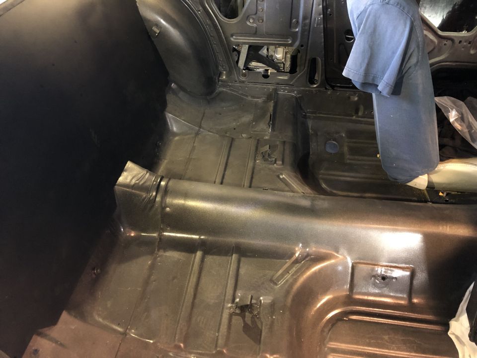 Bare metal floor pan and transmission tunnel inside stripped vehicle body