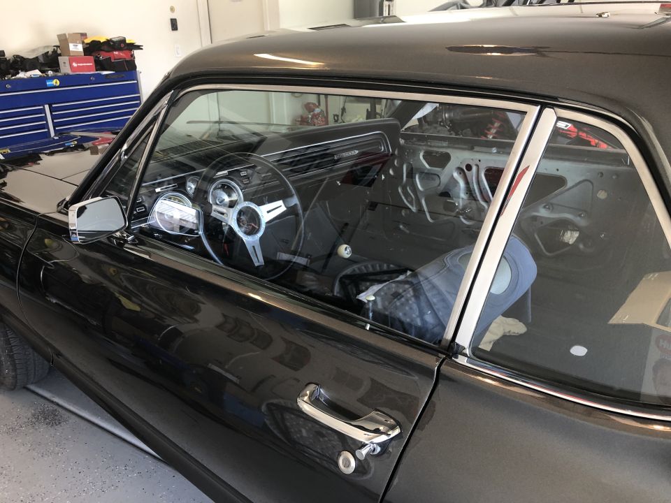 Interior of a classic car, likely a 1967 Mercury Cougar, showing the steering wheel, dashboard, and door panel. The interior is partially disassembled
