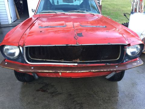 1967 Ford Mustang - The front of a red 1967 Ford Mustang shows signs of wear, including a rusty bumper and chipped paint.
