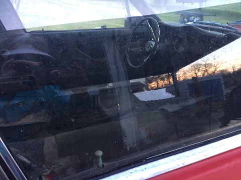 1967 Ford Mustang - View through the window of a car's interior, with reflections of the outdoors visible on the glass.