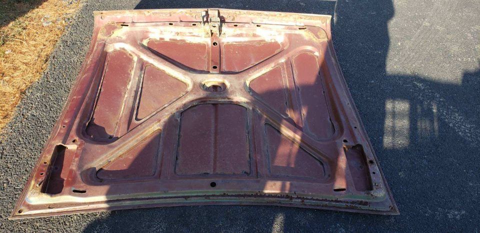 Underside of a rusty car hood, showing structural bracing