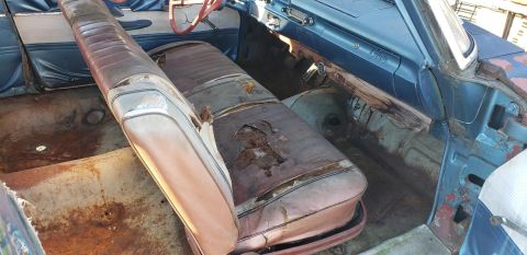 1962 Ford Galaxie - The interior of a 1962 Ford Galaxie shows significant wear and tear on the seats and rust on the floor.