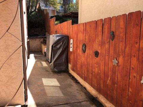 1992 Jeep Wrangler - A tarp covers a grill next to a wooden fence with decorative items.
