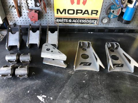 1992 Jeep Wrangler - Various metal suspension parts are laid out on a workbench, with a Mopar sign in the background.