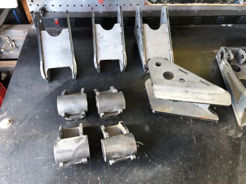 1992 Jeep Wrangler - Various metal suspension components, including brackets and bushings, are arranged on a workbench.