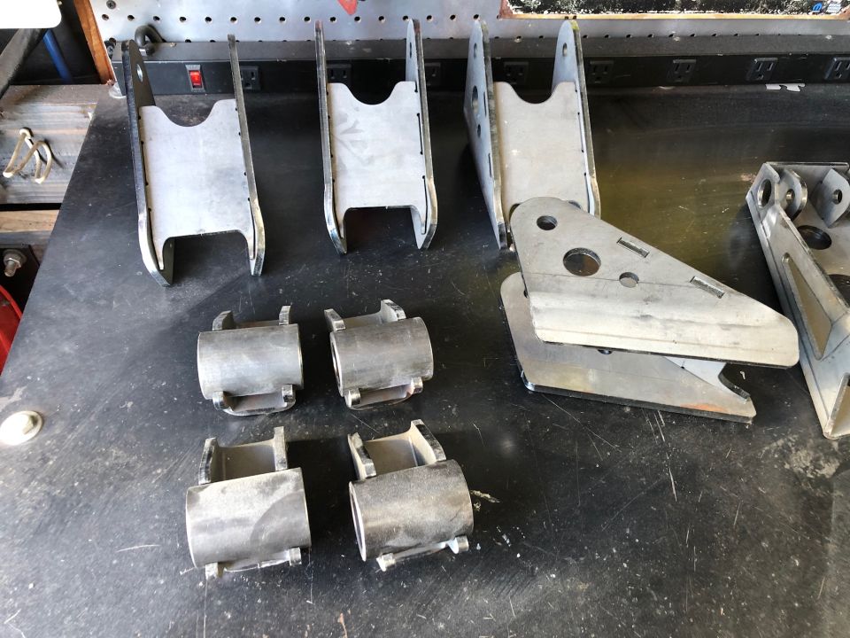 Metal suspension brackets and bushings laid out on a workbench