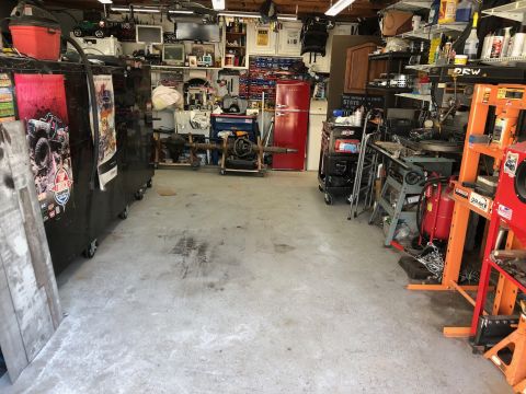 1992 Jeep Wrangler - A cluttered garage scene with storage, tools, and a red refrigerator.