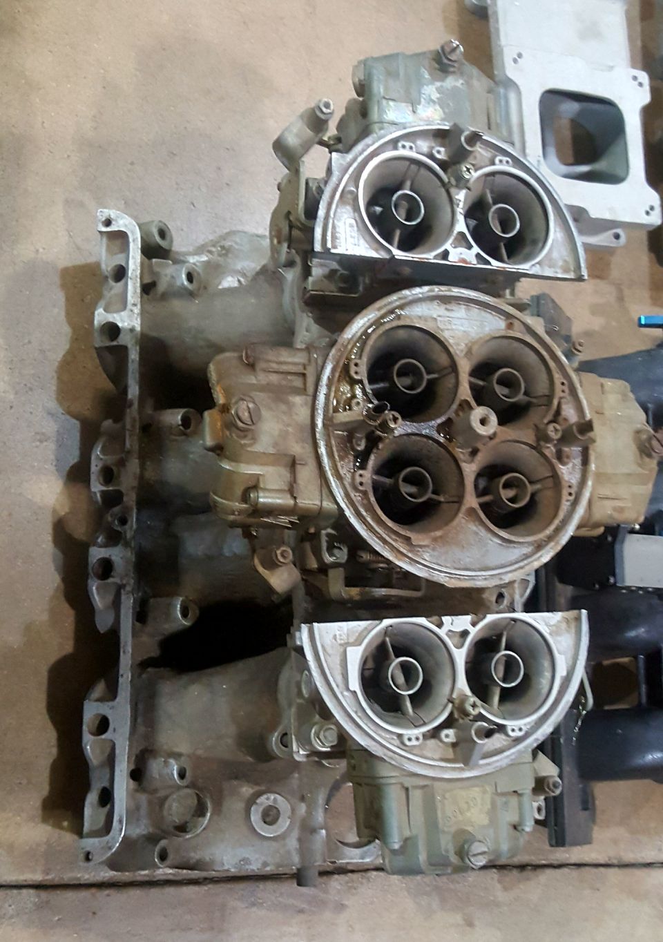 Disassembled tri-power three two-barrel carburetor manifold setup on bench