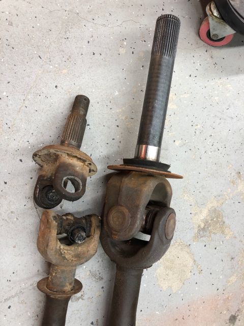 1992 Jeep Wrangler - Two driveshaft assemblies with universal joints are shown on a concrete floor.