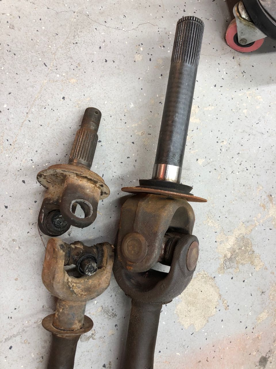 Two driveshaft assemblies with universal joints on a concrete floor