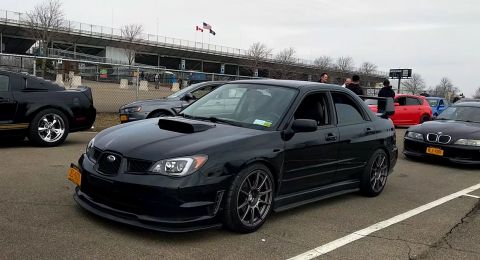 2006 Mitsubishi Evolution - A black 2006 Subaru Impreza WRX STI is parked at an event with other vehicles visible.