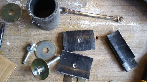 Rubber hose, bolts, washers, and a wrench laid out on a wooden workbench