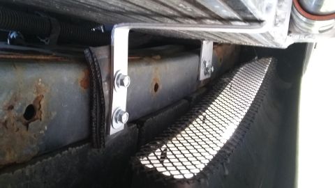 Undercarriage with rusty frame, custom metal brackets bolted on, and black mesh