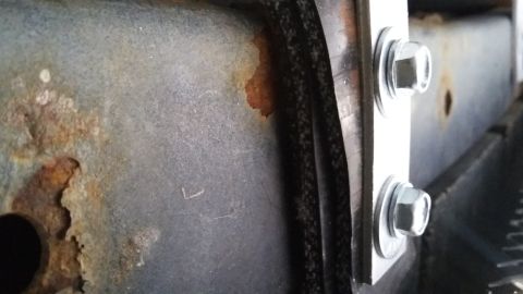 Rusted metal frame with two bolts securing a bracket