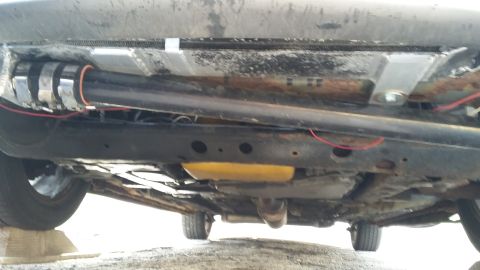 Underside view of a car, showing the exhaust system, frame, and some wiring
