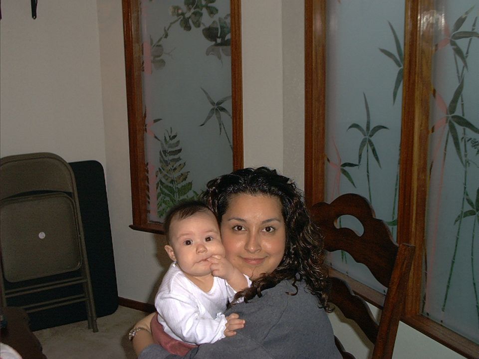 Woman holding a baby indoors near frosted decorative windows