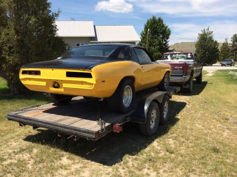1969 Chevrolet Camaro - A yellow and black 1969 Chevrolet Camaro is transported on a trailer, with a pickup truck in tow.