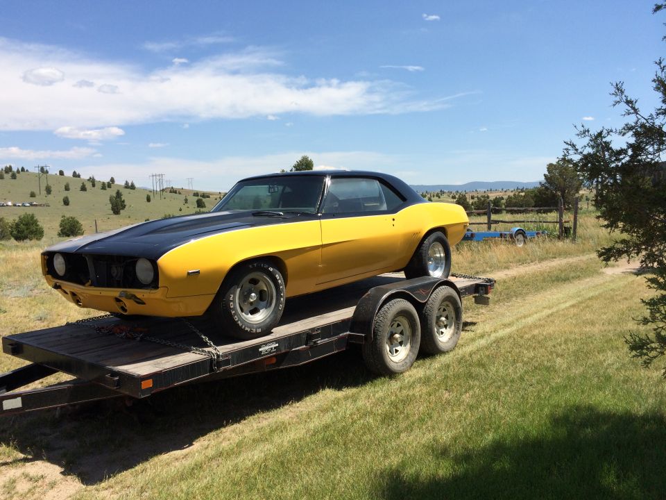 Yellow and black coupe on a trailer, looks like a 1969 Camaro but the grille is wrong