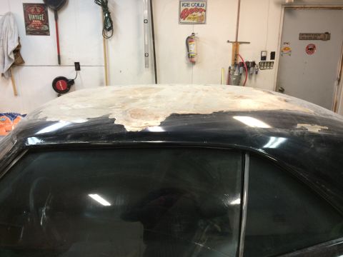 1969 Chevrolet Camaro - The roof of a car is being repaired with body filler in a garage setting.