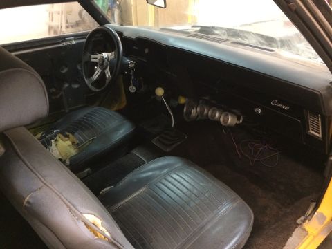 1969 Chevrolet Camaro - The interior of a 1969 Chevrolet Camaro shows worn seats, a manual transmission, and aftermarket gauges.