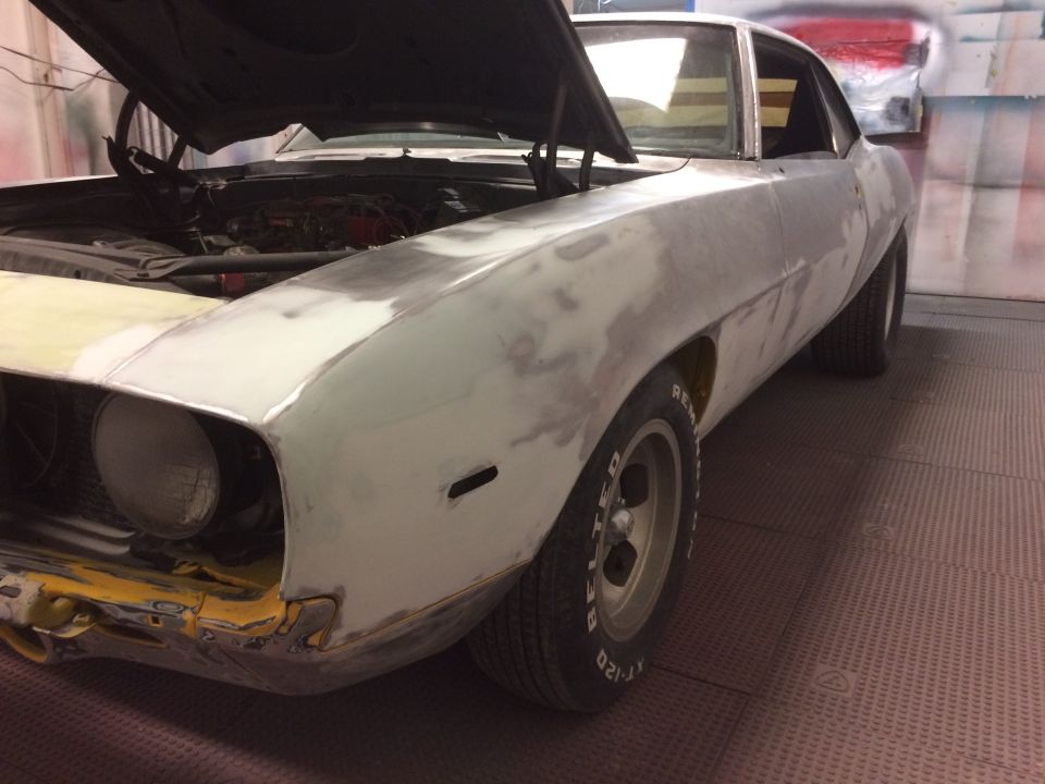 Front fender and hood of a 1969 Chevrolet Camaro being prepped for paint, showing primer and body filler