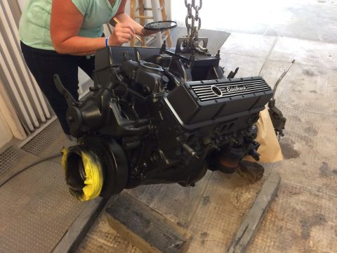 1969 Chevrolet Camaro - A person is painting a black engine that is suspended by chains, an Edelbrock valve cover.