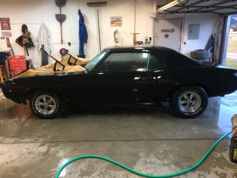 1969 Chevrolet Camaro - Side view of a black 1969 Chevrolet Camaro in a garage, with the hood covered.