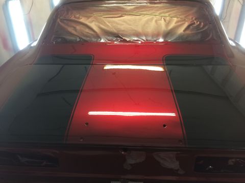 1969 Chevrolet Camaro - The rear of a car is shown with racing stripes being applied to the trunk and rear window area.