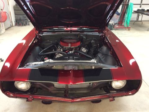 1969 Chevrolet Camaro - The engine bay of a classic red Chevrolet Camaro is visible with the hood raised.