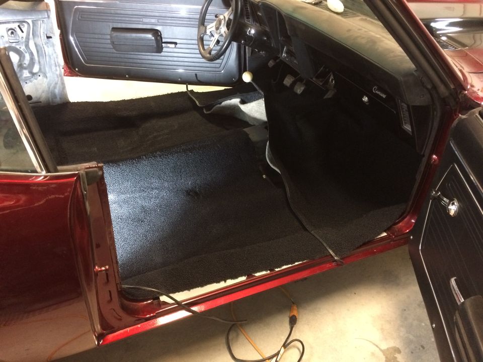 Interior of a 1969 Chevrolet Camaro with black carpet installed. Door panels and dashboard are visible
