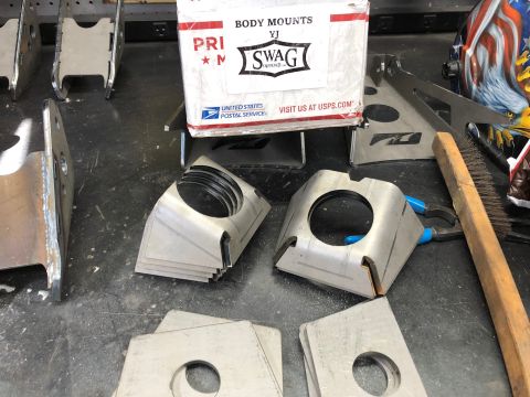 1992 Jeep Wrangler - Metal brackets and a box of YJ body mounts are laid out on a workbench, possibly for installation.