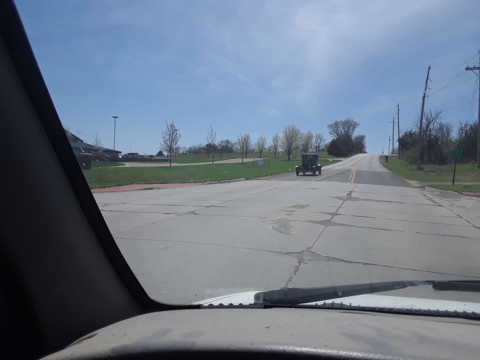 Antique car with a boxy rear, seen from behind on a paved road