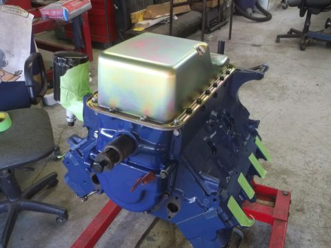 1967 Ford Galaxie - A blue engine block with a gold oil pan is mounted on a red engine stand in a workshop.