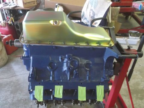 1967 Ford Galaxie - A blue engine block with a gold oil pan is mounted on a red engine stand, ready for assembly.
