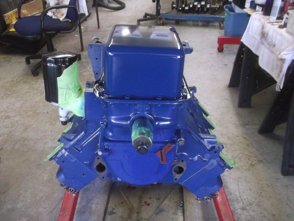 Blue engine block on a stand, with oil filter attached. Some parts are covered with green tape