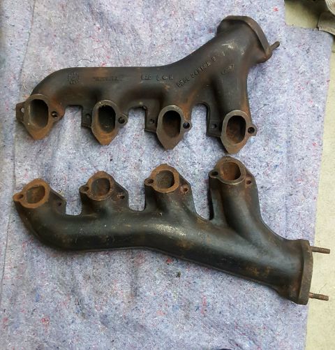 1973 Ford Mustang - Pair of cast iron exhaust manifolds shown on a grey cloth. Text is visible on the upper manifold.