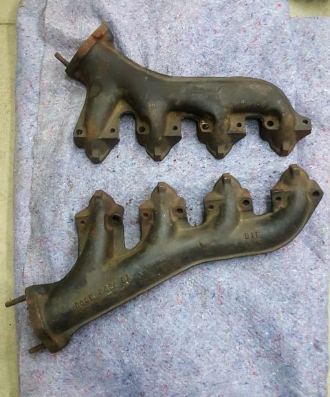 1973 Ford Mustang - Two cast iron exhaust manifolds are laid out on a textured blanket, showing visible part numbers.