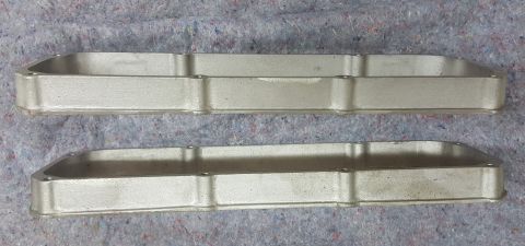 1973 Ford Mustang - Two aluminum valve covers are shown from above, resting on a grey, textured surface. A Supermotors.net logo is in the lower right corner.