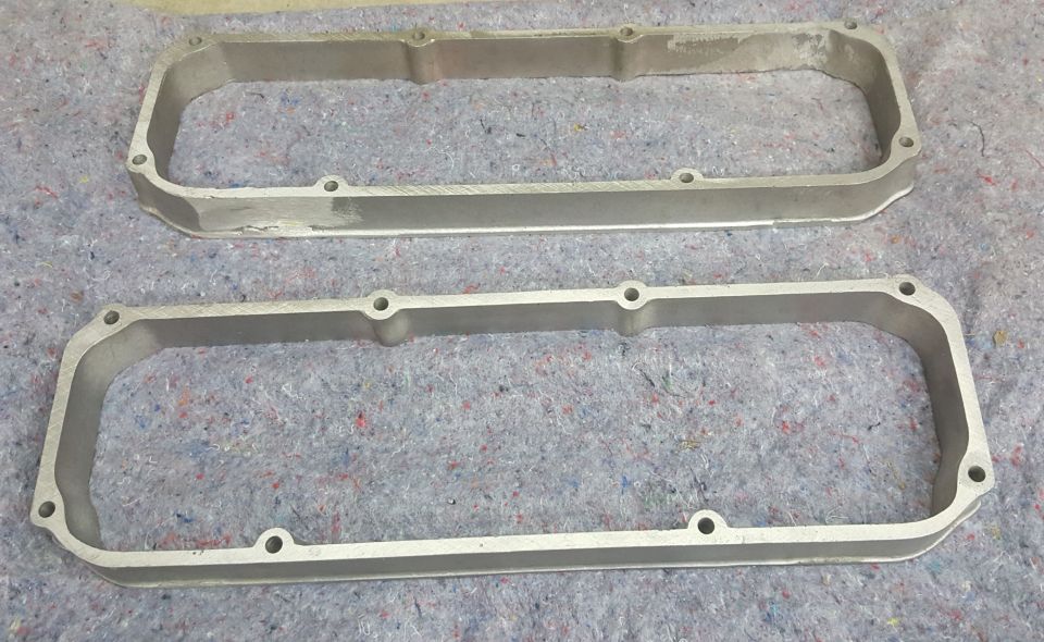 pair of aluminum valve covers on a gray carpeted surface