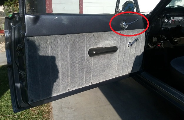 Interior of a car door showing grey fabric panel, black armrest, and chrome door handle