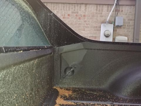 1977 Ford Ranchero - The textured surface of a truck bed is visible, with a tie-down anchor and water on the rear window.