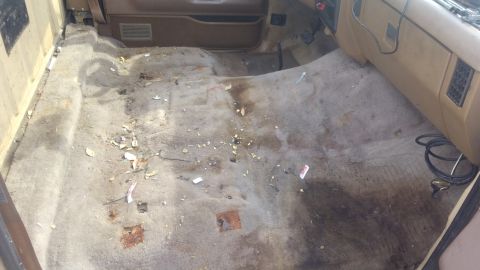 1990 Ford F-250 - The interior of a 1990 Ford F-250 shows a dirty carpet with debris scattered across the floor.