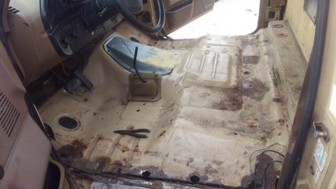 1990 Ford F-250 - The interior of a 1990 Ford F-250 shows a tan cab with the flooring removed, revealing rust and exposed metal.