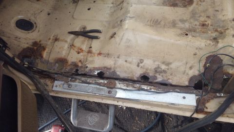 1990 Ford F-250 - Rusted interior floor pan with pliers visible, likely from a vehicle in poor condition.