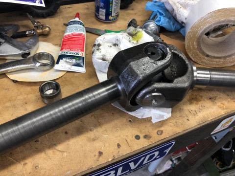 1992 Jeep Wrangler - A driveshaft universal joint sits on a workbench next to a tube of grease and a wrench.