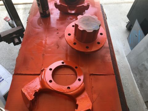 1992 Jeep Wrangler - Several orange painted vehicle axle components are laid out on a table covered with orange paper.