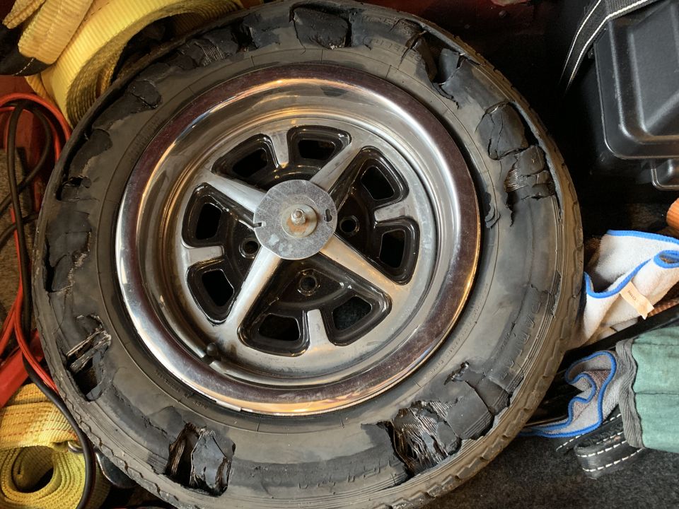 Tire with severe sidewall damage and a chrome five-spoke wheel