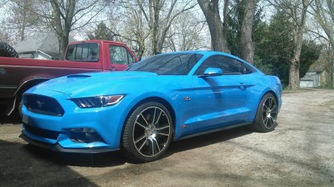 2017 Ford Mustang - A bright blue 2017 Ford Mustang is parked in a driveway next to a red pickup truck.