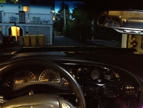 2000 Pontiac Grand Prix interior showing dashboard gauges, vents, and view through windshield of a house and d
